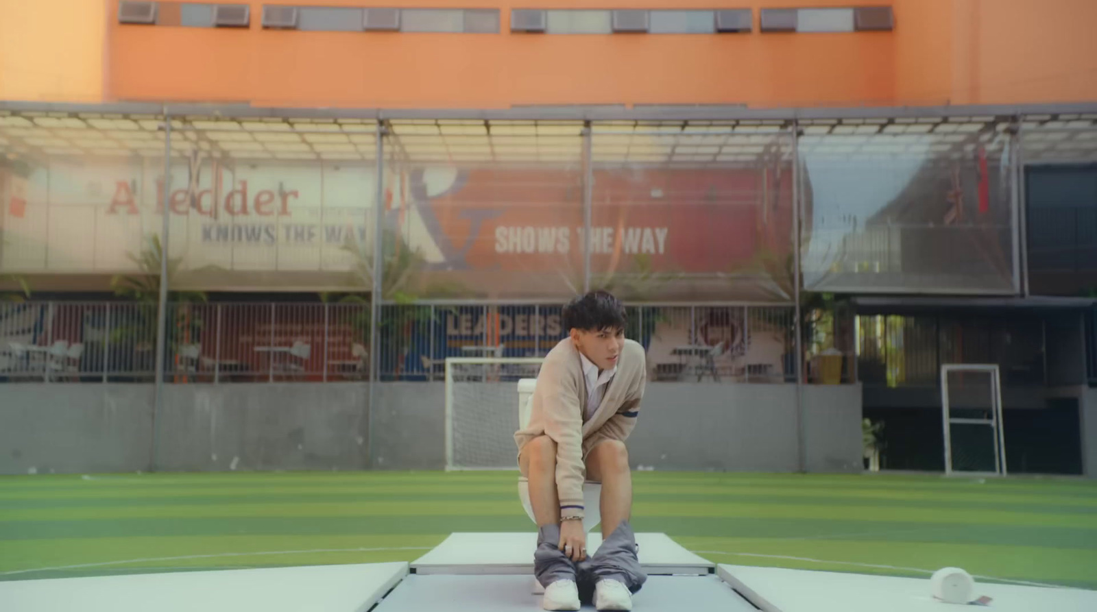 a boy is sitting on a trampoline in front of a building