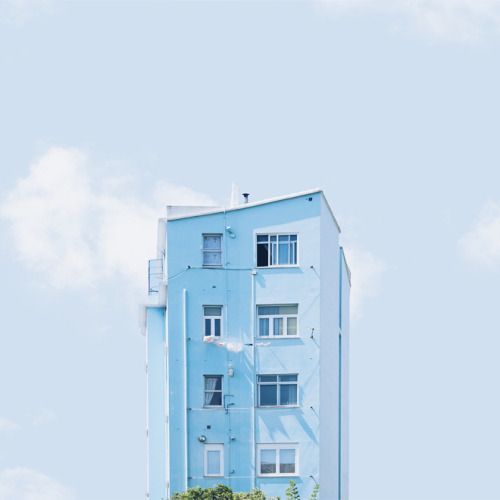 a tall blue building sitting on top of a lush green field