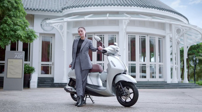 a woman in a suit standing next to a scooter