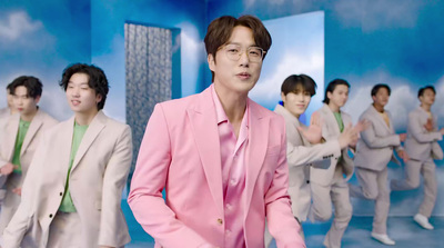 a man in a pink suit standing in front of a group of other men