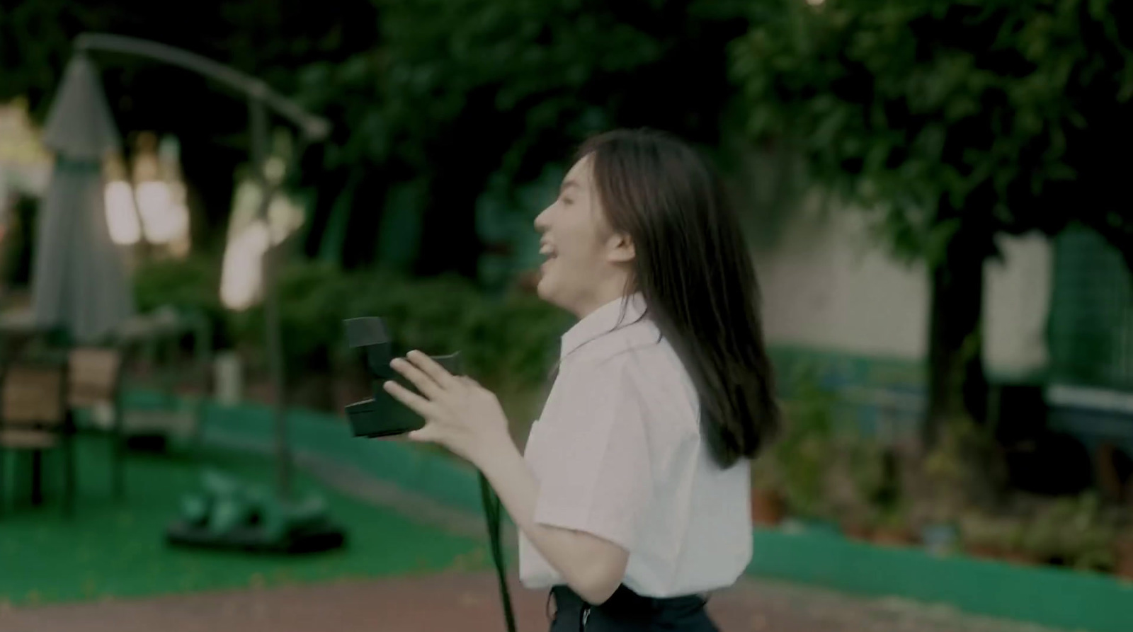 a woman standing in a park holding a camera