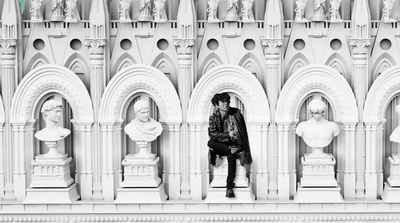 a person sitting on a ledge in front of a building