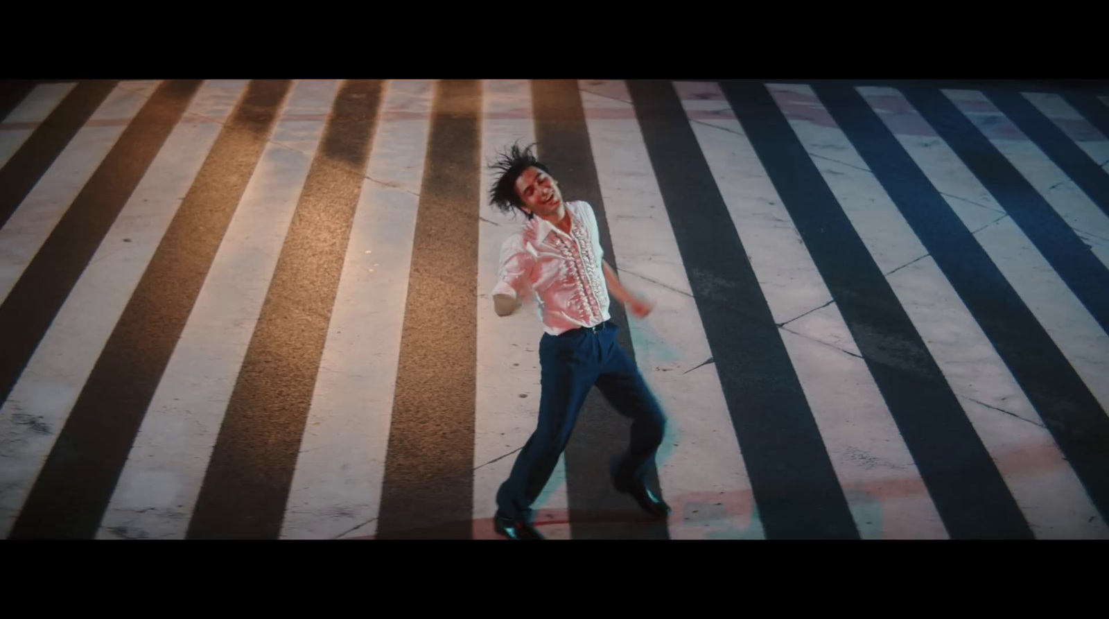 a man walking across a cross walk in the middle of the street