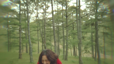 a woman in a red jacket walking through a forest