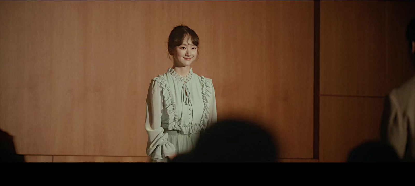 a woman standing in front of a wooden wall