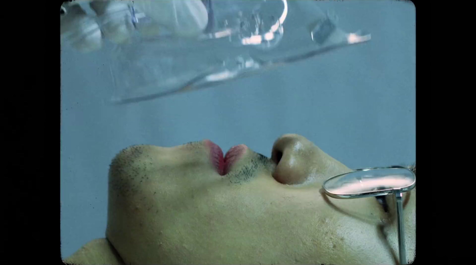 a man laying down with his head under a glass