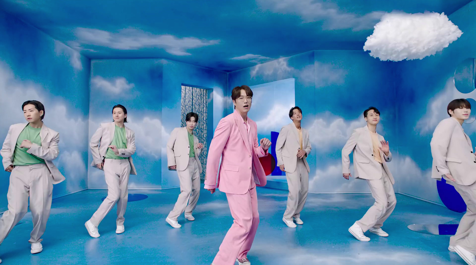 a man in a pink suit is dancing in front of a group of other men