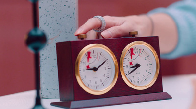 a person holding a clock on top of a table