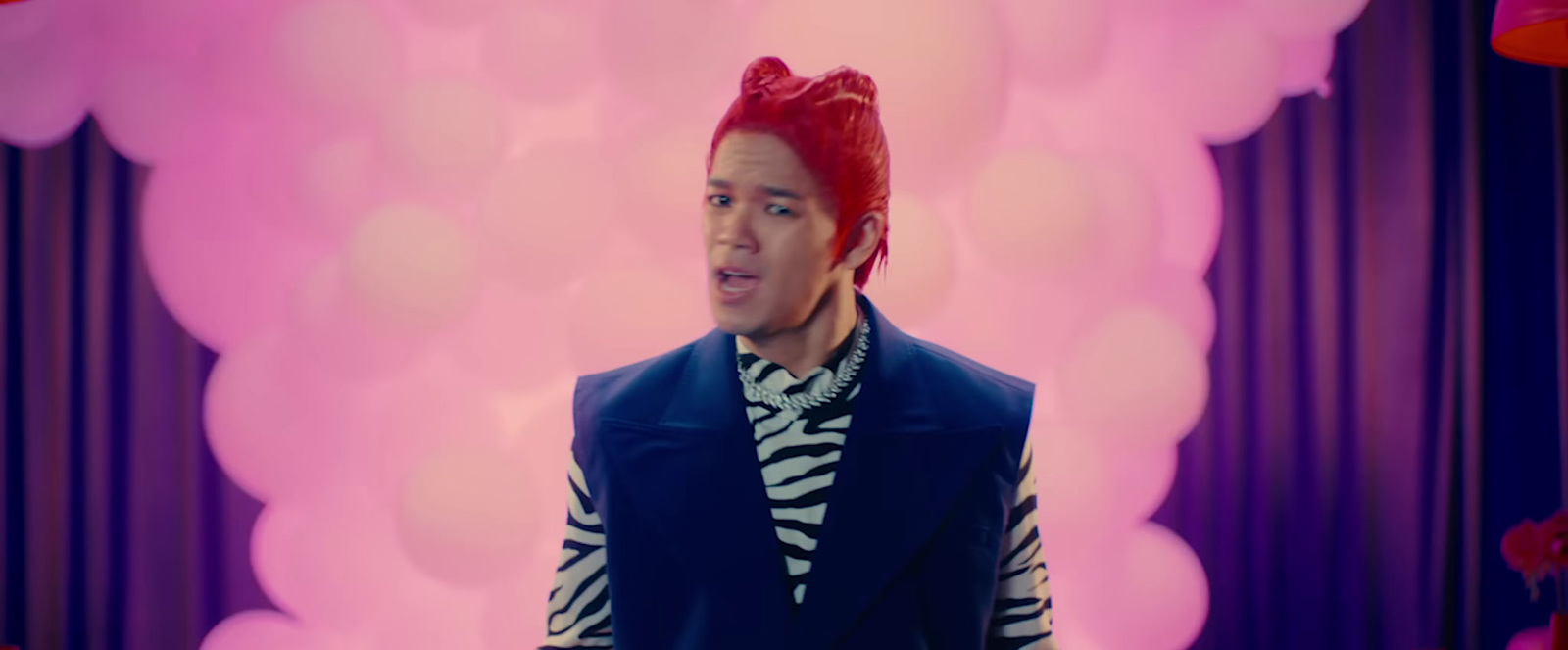 a man with red hair wearing a blue vest