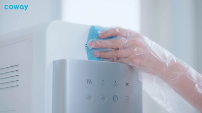 a person is cleaning a microwave with a blue towel