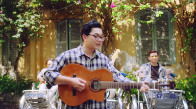 a man playing a guitar in front of a building