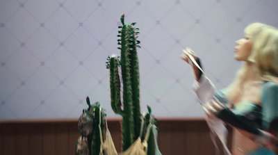 a woman standing next to a tall green cactus