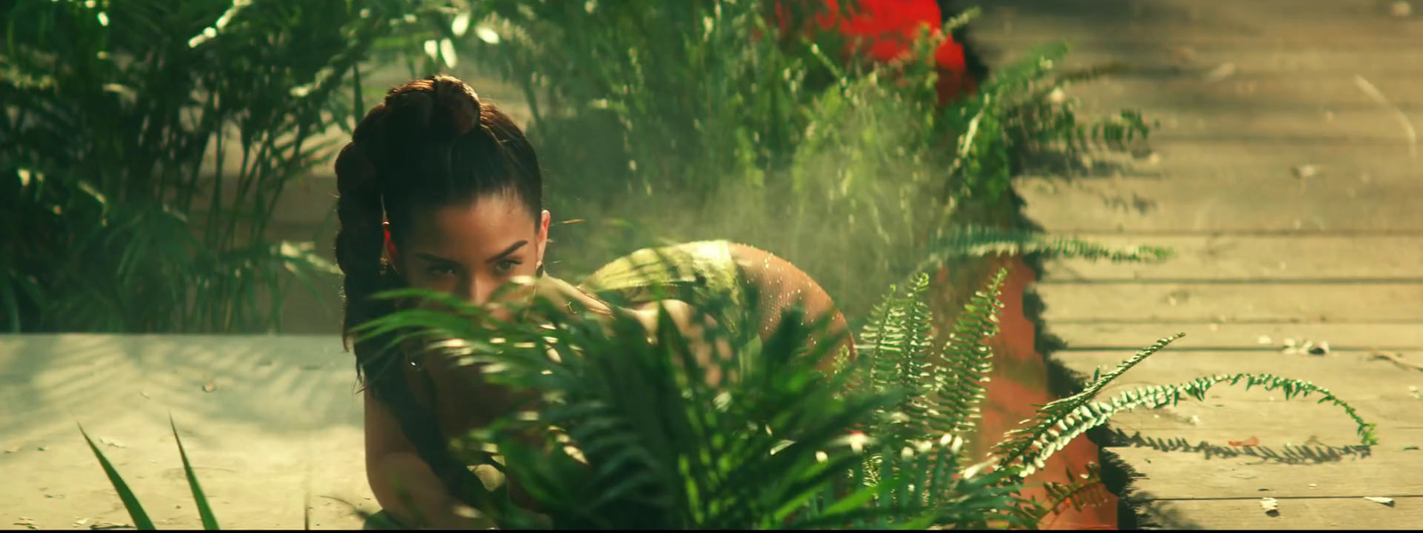 a woman sitting on the ground next to a plant