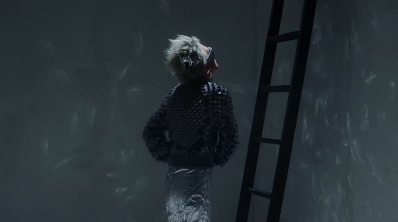 a man standing next to a ladder in a dark room