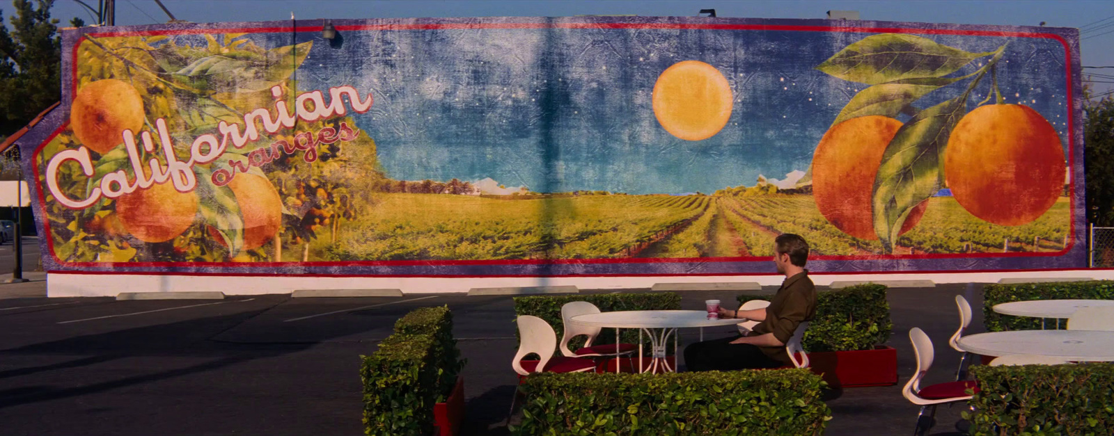 a person sitting at a table in front of a large advertisement