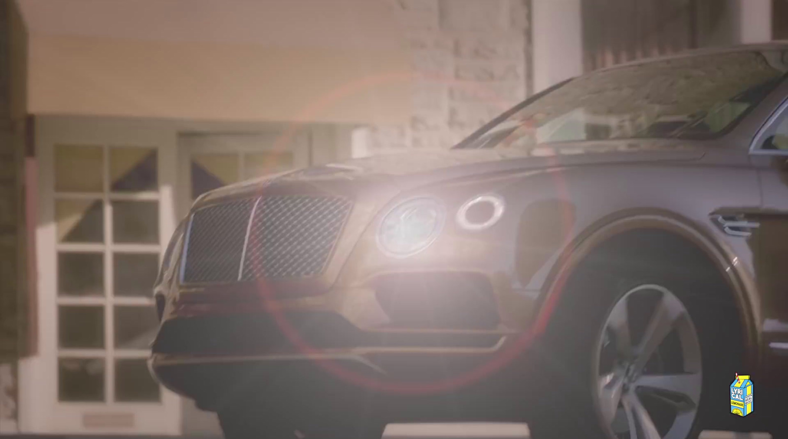 the front end of a brown car parked in front of a building