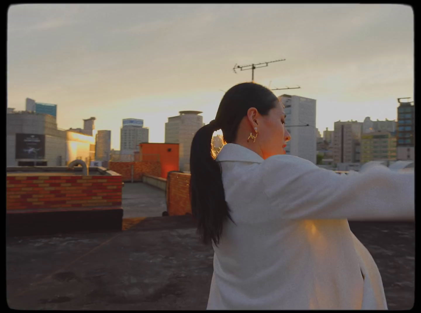 a woman standing on top of a roof next to a tall building