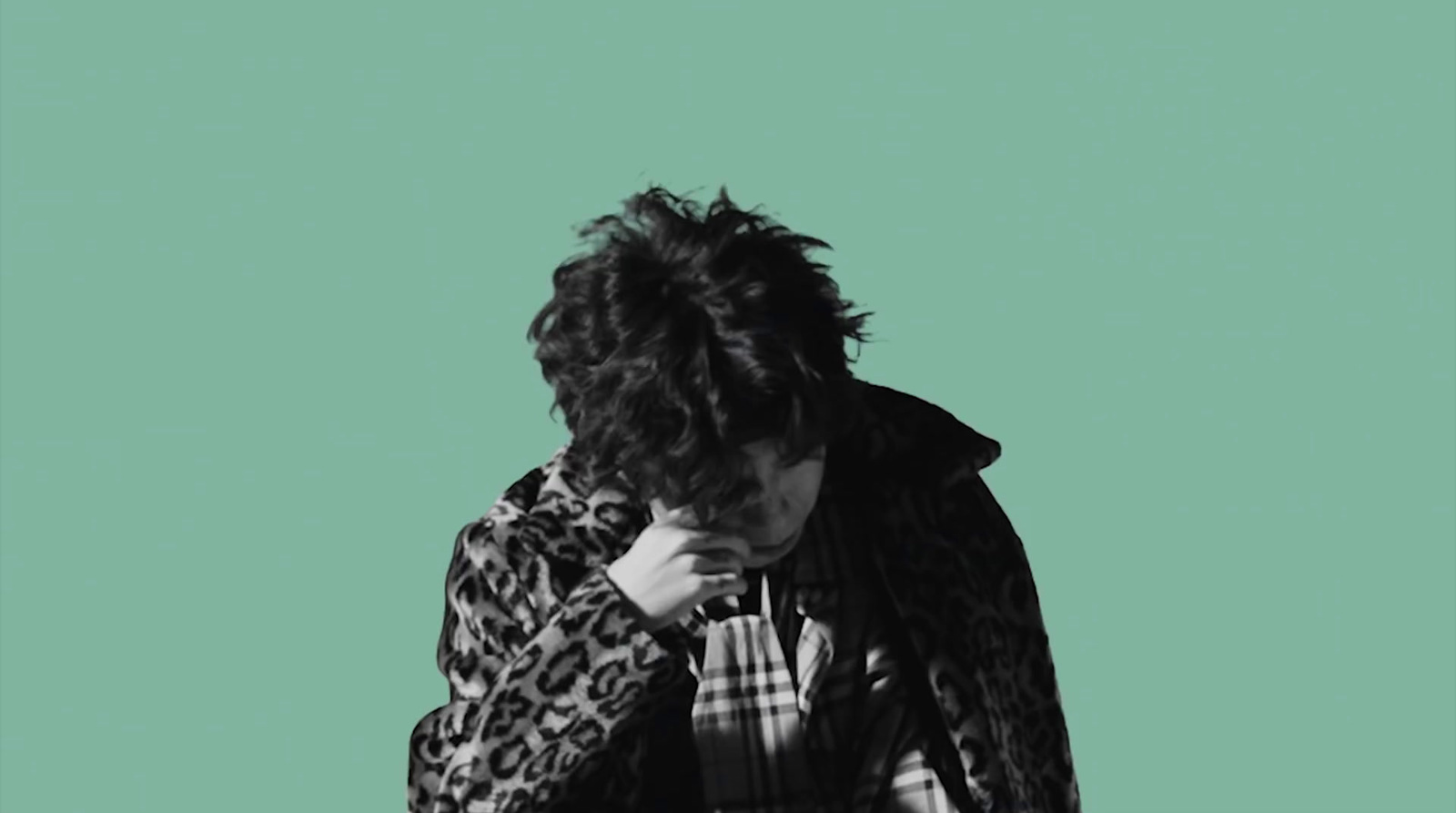 a man in a leopard print jacket is covering his face with his hand