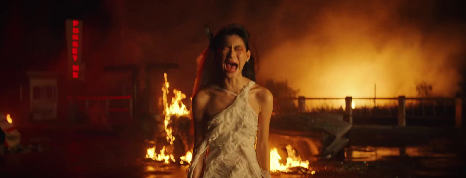 a woman in a white dress standing in front of a fire