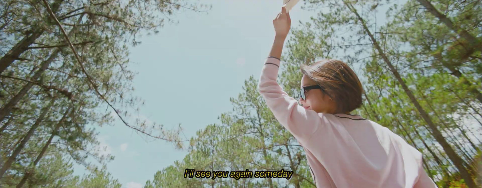 a girl in a pink shirt reaching up into the sky