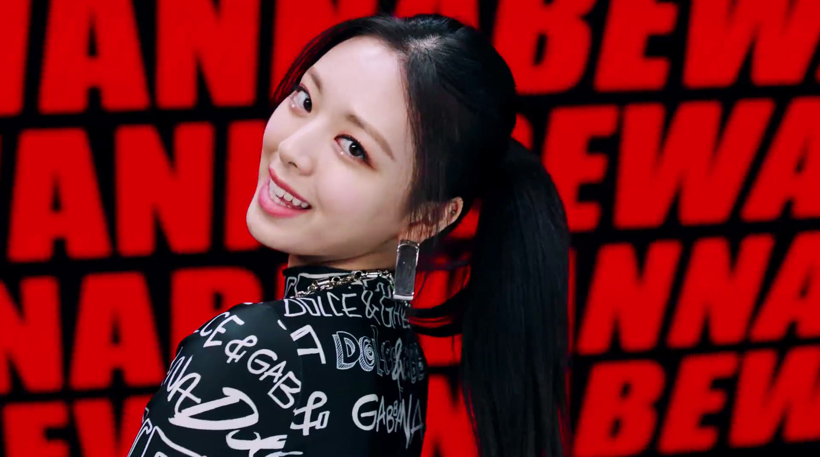 a woman with long black hair standing in front of a red wall