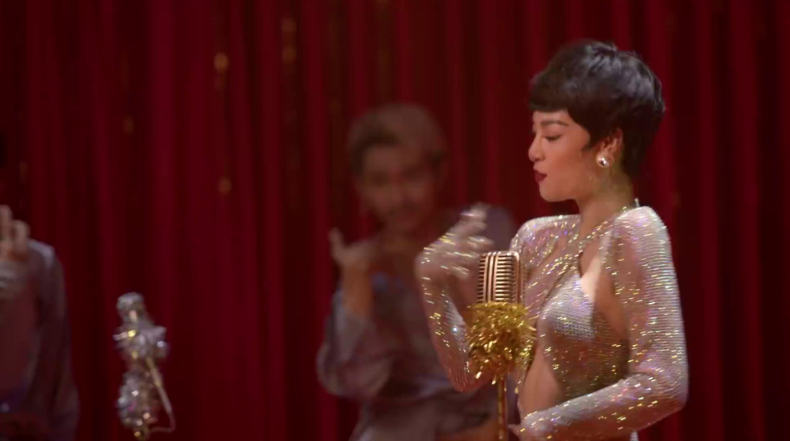 a woman standing next to a man in front of a red curtain