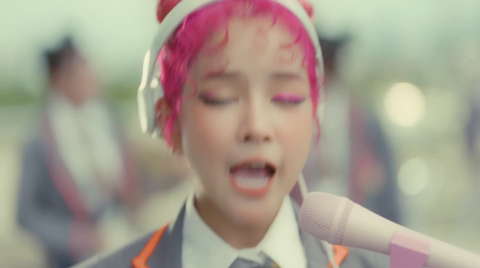 a woman with pink hair wearing headphones and singing into a microphone