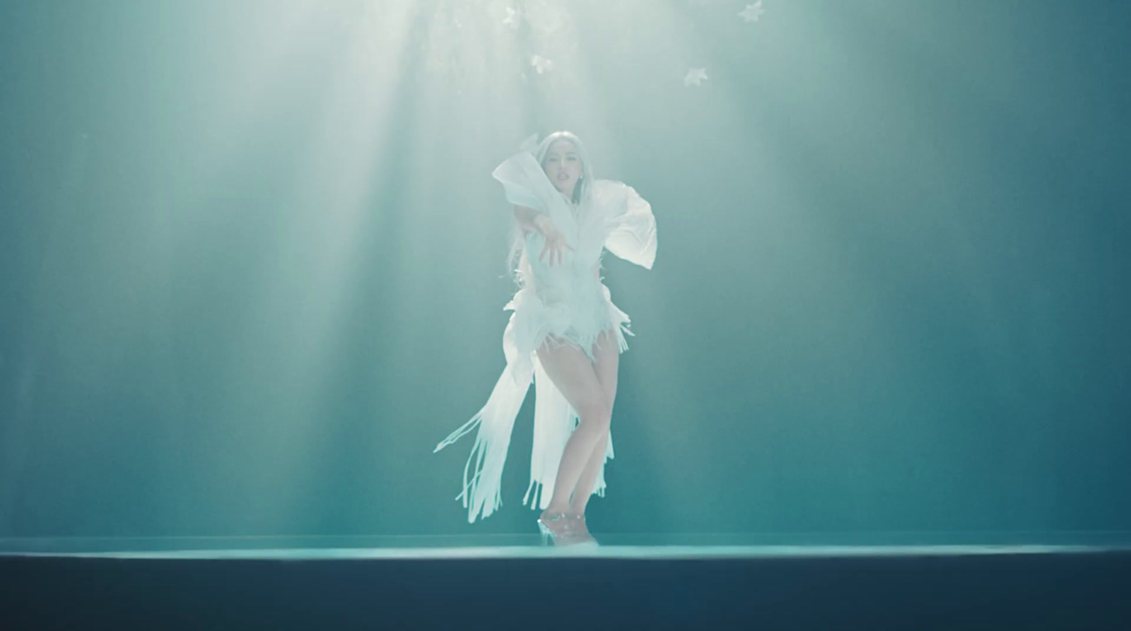 a woman in a white dress standing under a light