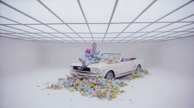 a man sitting on top of a car surrounded by flowers