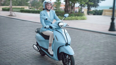 a woman riding on the back of a blue scooter