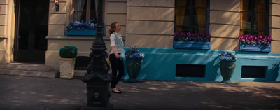 a woman standing on a sidewalk in front of a building