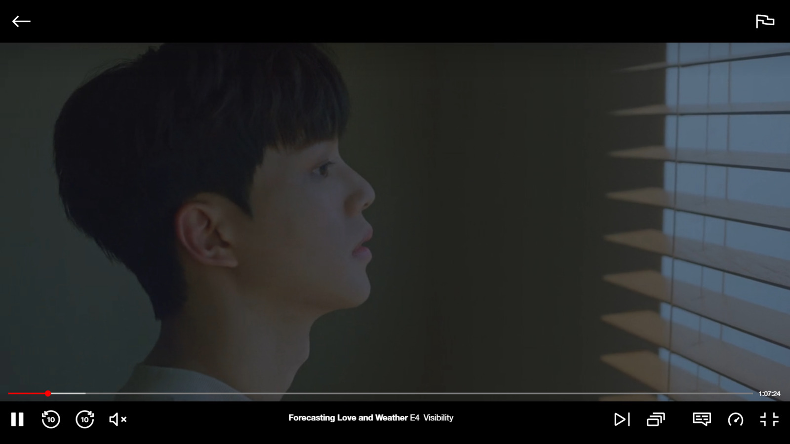 a boy looking out of a window with blinds closed