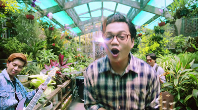 a man holding a guitar in a greenhouse