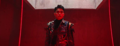 a man in a leather jacket standing in a red room