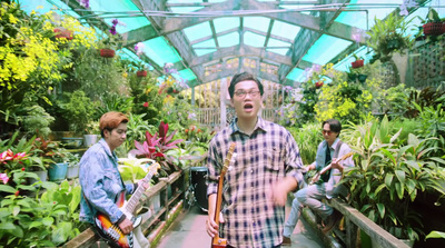 a man standing in a greenhouse holding a guitar