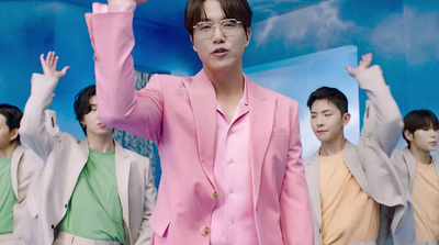 a man in a pink suit standing in front of a group of people