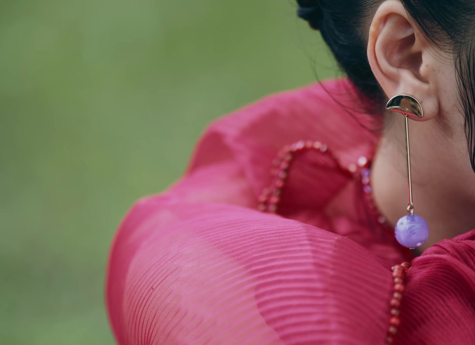 a woman wearing a pink shirt and a pair of earrings