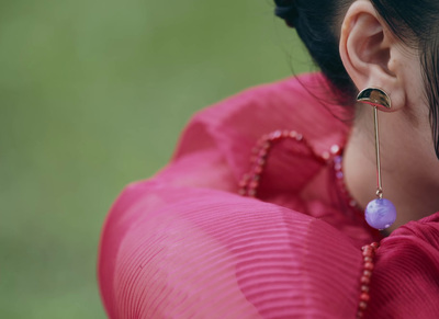 a woman wearing a pink shirt and a pair of earrings