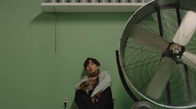 a man sitting on the floor next to a fan