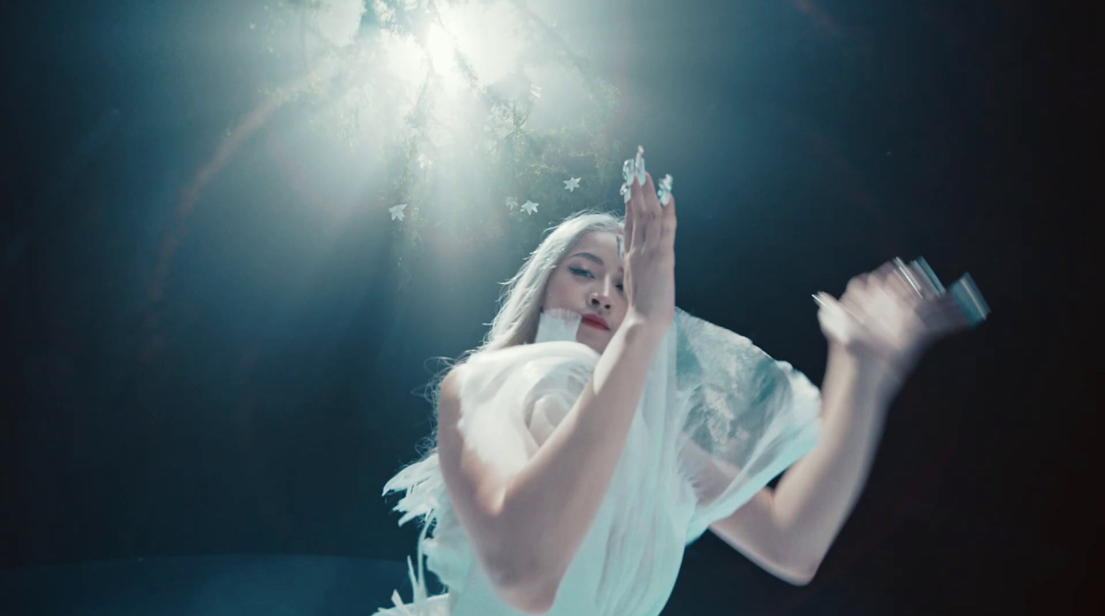 a woman in a white dress holding her hands up in the air