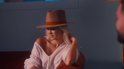 a woman sitting on a couch wearing a hat