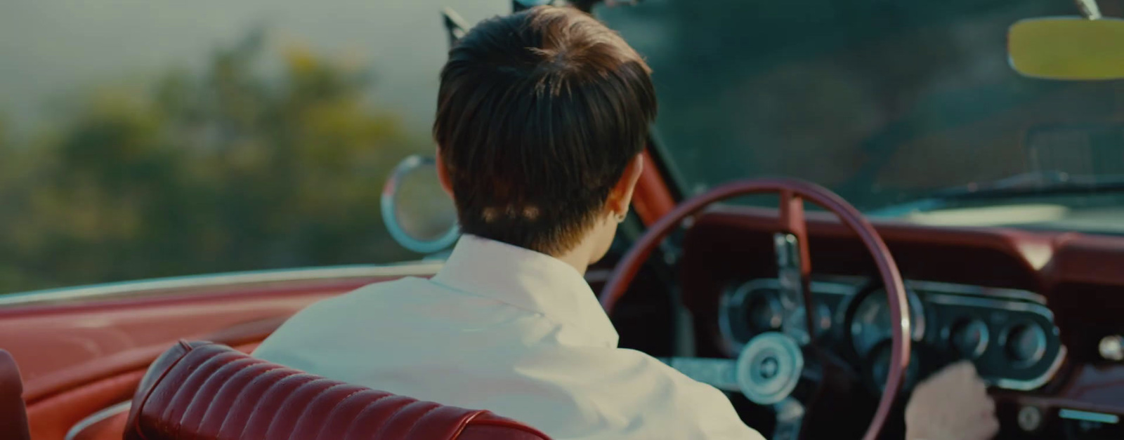 a woman sitting in a car with a steering wheel