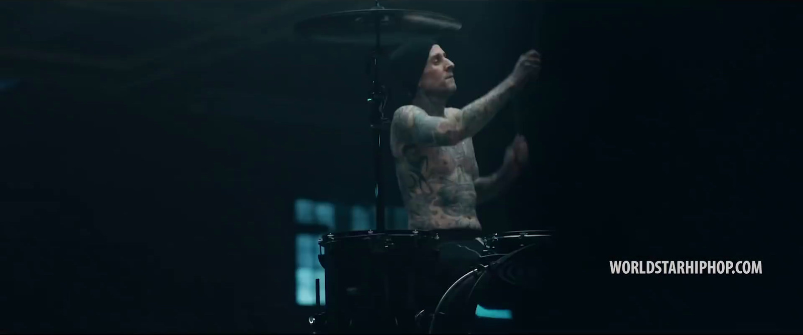 a man with tattoos on his body playing drums