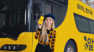 a woman standing in front of a yellow bus