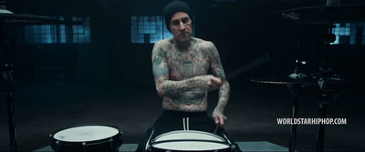 a tattooed man playing drums in a dark room