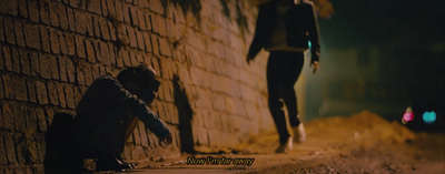 a person sitting on the ground next to a brick wall