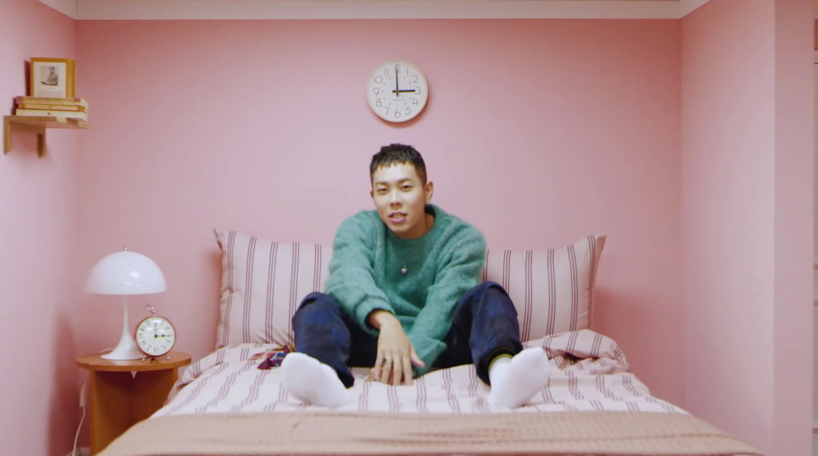 a man sitting on top of a bed in a pink room