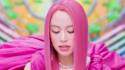 a woman with pink hair and a pearl necklace