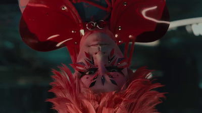 a woman wearing a red mask with feathers on her head