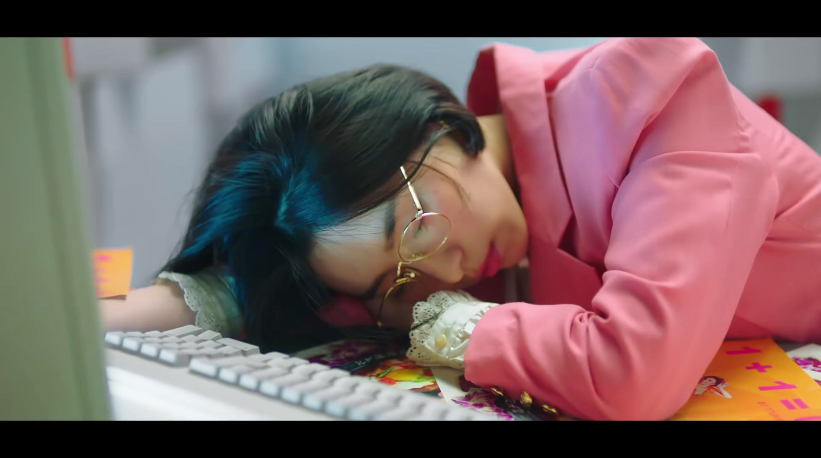 a woman in a pink jacket leaning her head on a keyboard